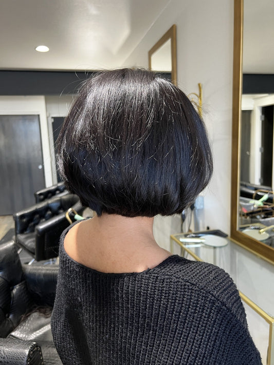 Back view of a dark, glossy graduated bob with a crisp, stacked nape.